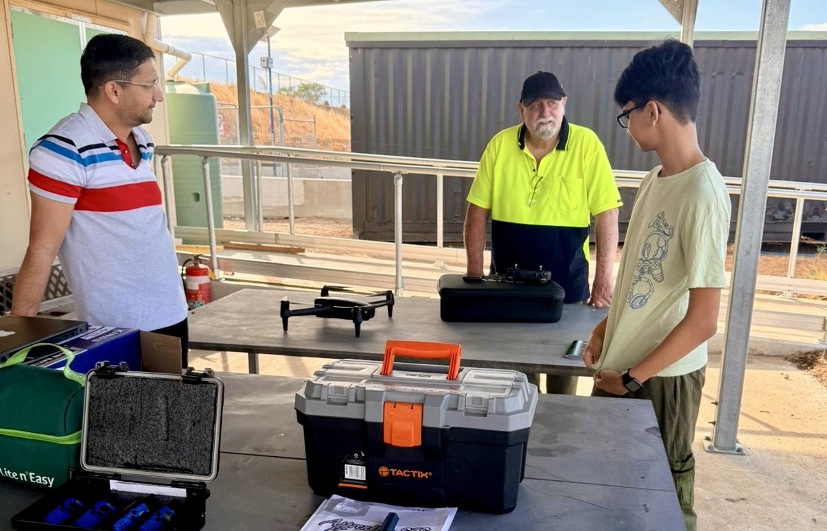 Members demonstrating a drone and equipment under the clubhouse shelter