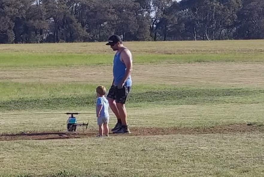 A father and young child with a helicopter on the grass