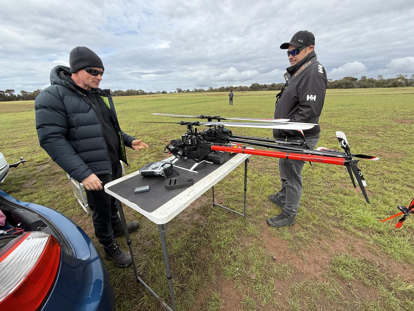 Member holding a radio transmitter beside his helicopter