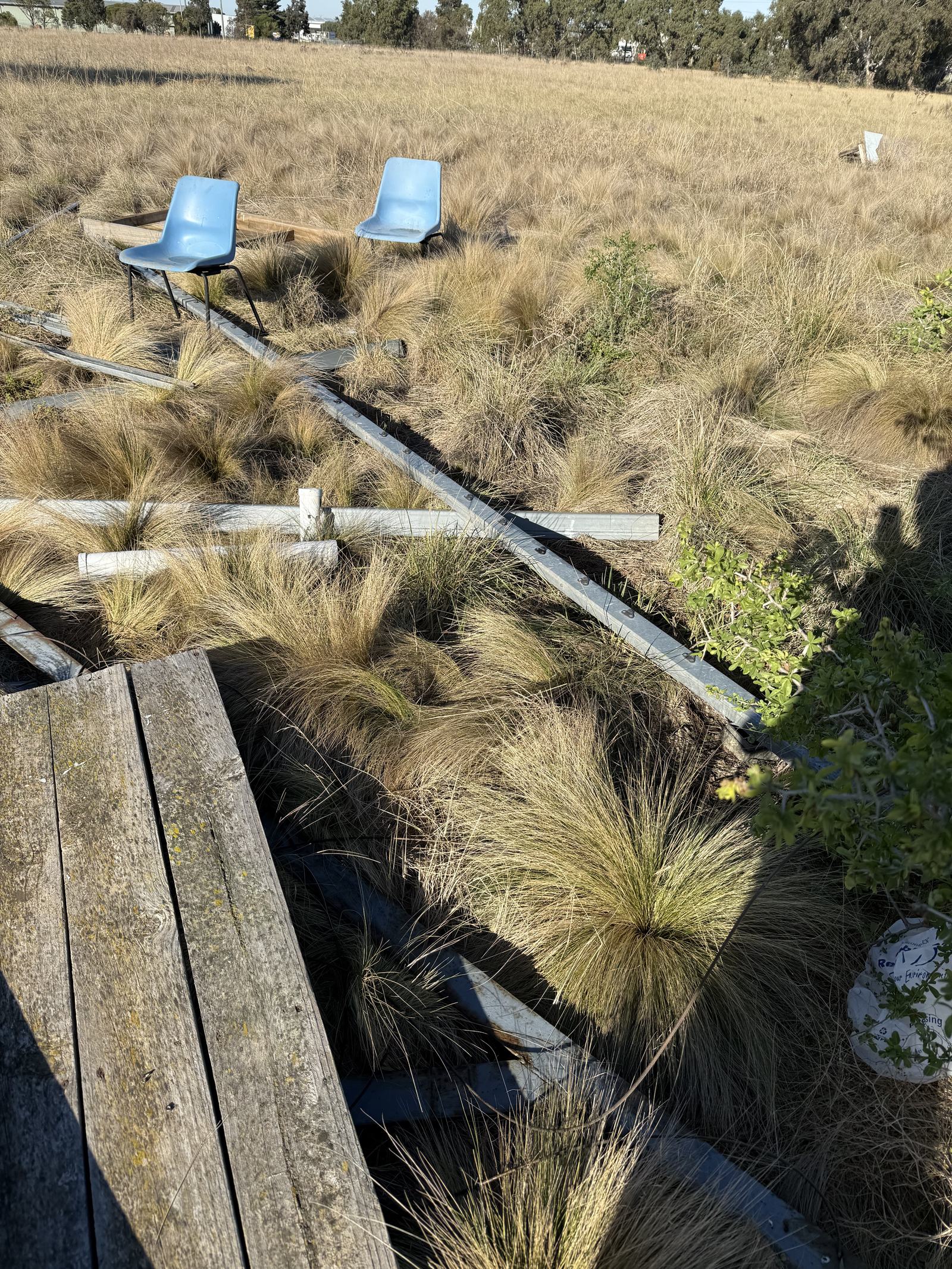 Chairs left behind in overgrown grass at the former field